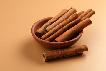 Cinnamon sticks in a earthen  bowl,  on light brown background, selective focus.