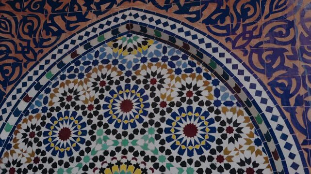 Close-up view of traditional Moroccan tile mosaic with intricate geometric and floral patterns. The vibrant colors and handcrafted details create a visually rich display of Moroccan art