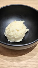 Mashed potatoes in a black cup on a wooden table