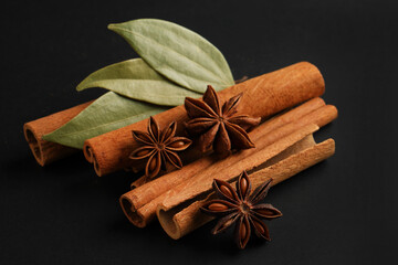 traditional spices anise stars, cinnamon and bay leaf on black background