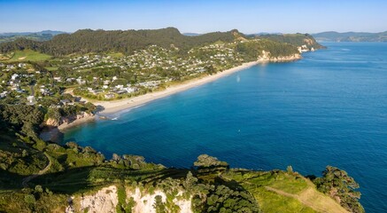 Aerial view of a coastal Hahei town, homes nestled beside a sandy beach, and turquoise water. Tranquil seaside community, Coromandel Peninsula, New Zealand © Zenstratus