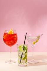 A variety of cocktails arranged on a table against a light pink background