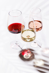 Three wine glasses filled with red, white, and rose wine