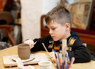 A boy creates a pot in a pottery workshop