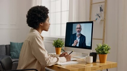 African American adult student having virtual meeting online call educational webinar chatting with senior teacher at home office writing notes. Remote working online. - Powered by Adobe
