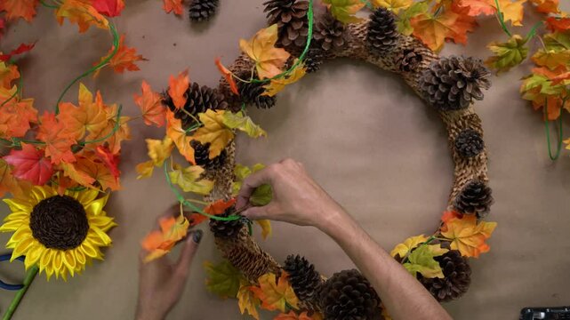 Artist assembling autumn themed wreath capturing season&rsquo;s vibrant charm