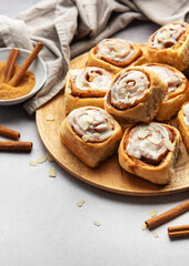 Freshly baked cinnamon rolls with icing and almond flakes on wooden plate