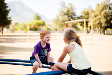 Fototapeta premium Smile, children and play on merry go round at park for summer fun, obstacle course and bonding together. Kids, ride and playground equipment with fine motor skills, active entertainment and childhood