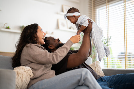 African family happy play at home, loving father holding and playing with baby while mother watches with joy, happy parenting moment full of love, affection, care and connection in cozy family at home