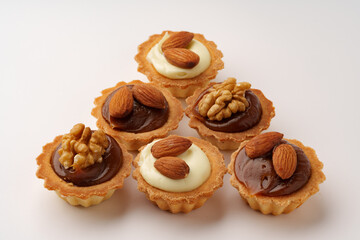 Delicious nut-topped pastry cups arranged in a decorative pattern on a white background