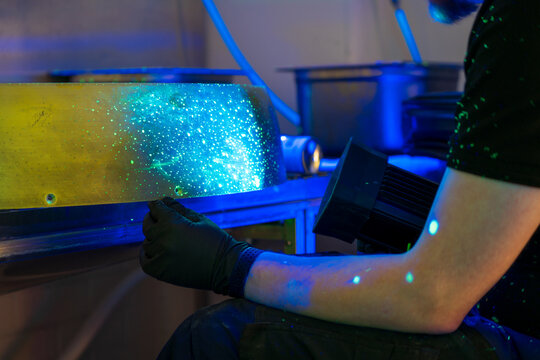 Industrial FPI testing showing fluorescent indications under blacklight examination. Non-destructive testing method revealing surface discontinuities with penetrant inspection