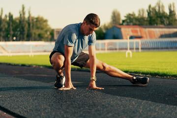 Young athlete stretches on the track during evening training session at a sports facility