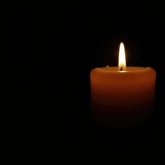 The soft glow of a candle flame on a black background creates a sense of calm, intimacy, warmth, gentle