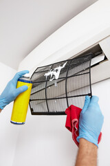 Man cleaning and maintaining air condition unit at home.