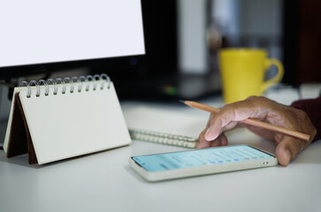 man hand using mobile phone to checking event plan. Job schedule, to do list. asian man working online with computer at home office