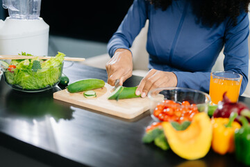 Smiling woman in a modern kitchen with fresh fruits, vegetables, blender, and orange juice,...
