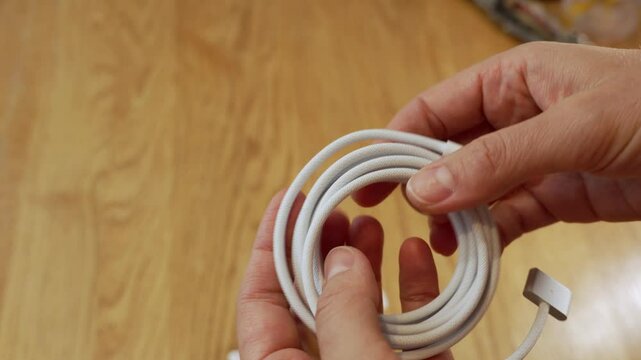 A person demonstrates the best methods for organizing and handling charging cables in a home setting, ensuring a neat and tangle-free arrangement while emphasizing ease of access.