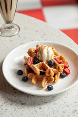 Portion of belgian waffles with ice cream and milkshake