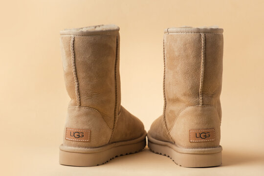 Kyiv, Ukraine - January 11, 2025: Winter beige Ugg Boots with fur on a beige background. Warm and comfort shoes Uggs on the pastel background. Studio shot with copy space