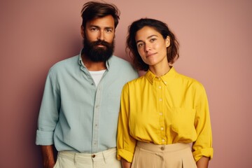 A man and a woman are standing next to each other, both wearing yellow shirts