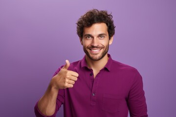 A man in a purple shirt is smiling and giving a thumbs up