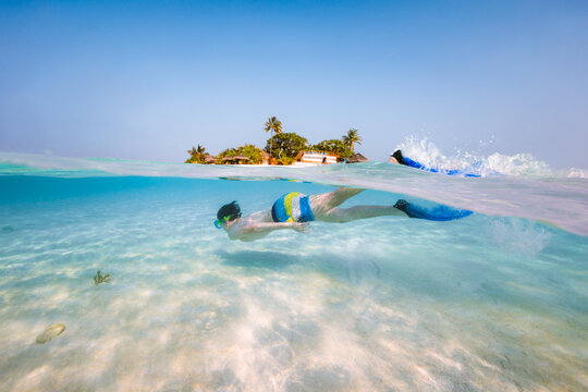 Over under image of boy snorkeling, Maldives
