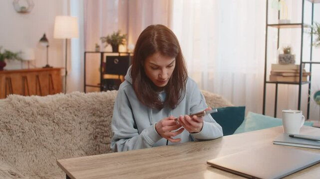 Young frustrated woman plugging charging cable into smartphone and unplugging it repeatedly as charger fails to work. Girl appears frustrated noticing cable is broken and unable to charge device.
