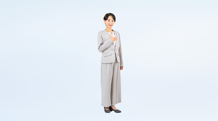 胸に手を当てるミドル女性ビジネスパーソンの全身写真（切り抜き背景透過PNGも販売しております。作成者リンクから「PNG」で検索してください）