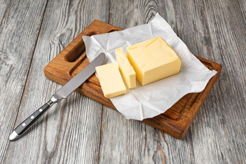 Butter slices with butter knife on wooden cutting board