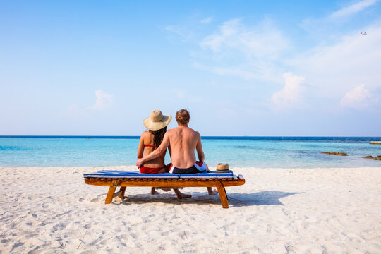 Couple sitting together on a lounge chair at the beach, Maldives