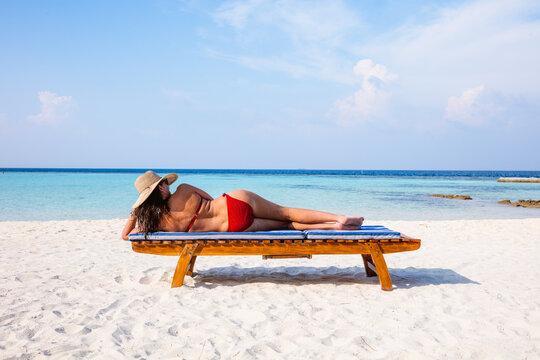 Woman relaxing on lounge chair on the beach, Maldives