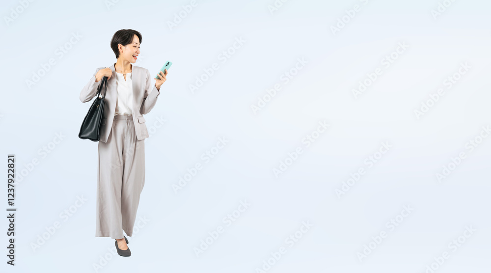 Aufkleber スマホを見ながら歩くミドル女性ビジネスパーソンの全身写真（切り抜き背景透過pngも販売しております。作成者リンクから「png」で検索してください）