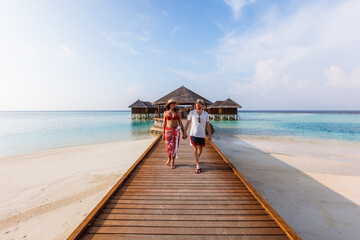 Adult couple walking on jetty in an island in the Maldives