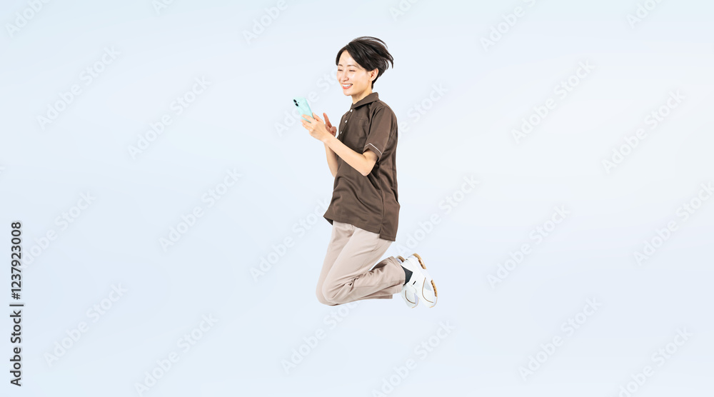 Poster スマホを見ながらジャンプするミドル女性スタッフの全身写真（切り抜き背景透過pngも販売しております。作成者リンクから「png」で検索してください）