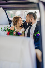 A stunningly beautiful couple dressed in elegant wedding attire is sharing a tender and intimate...