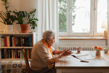 Side view of ederly woman looking sadly at few banknotes on table. Concept of financial concerns...
