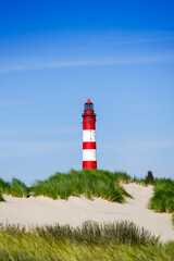 View of the dunes on the North Frisian island of Amrum. Landscape in the north. Nature on the North Sea island with a lighthouse.
