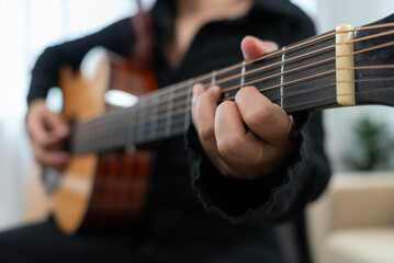 Fototapeta premium Close up female guitarist playing acoustic guitar at home studio. Positive musician girl enjoy instrumental music at home. Skill and practice, enjoyment and relax, entertainment and lifestyle.