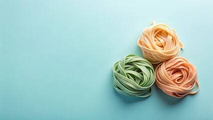 Fototapeta premium A vibrant trio of pastel-colored pasta nests arranged on a smooth, light-blue background offers a delightful culinary visual