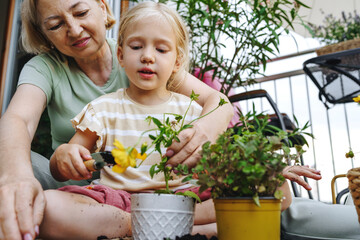 Woman and granddaughter planting on the balcony promoting sustainability and teamwork