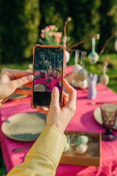 Hands of woman photographing Easter decoration through smart phone