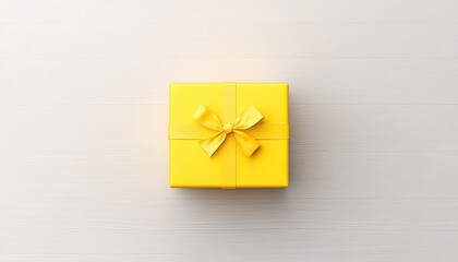 Bright yellow gift box with a ribbon on a light wooden surface, symbolizing celebration and joy