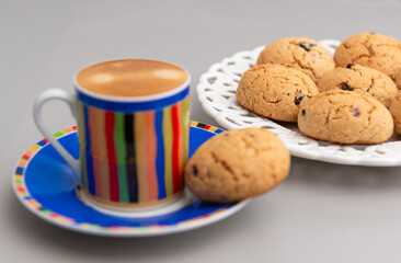 Coffee in a multicolor mug and cookies on a white plate