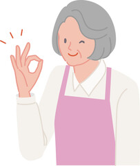 笑顔で手でOKポーズをするエプロンのシニア女性