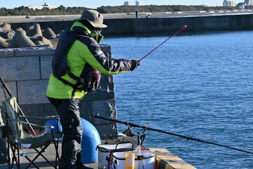 Obraz premium A scene of anglers on the embankment of a fishing port. Background material for holiday hobbies.