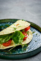 A vibrant and refreshing appetizer featuring a crispy tortilla filled with fresh tomatoes, herbs, and a creamy sauce.