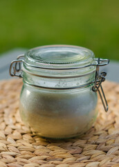Glass jar with homemade natural product on a woven mat, outdoor setting. High quality photo