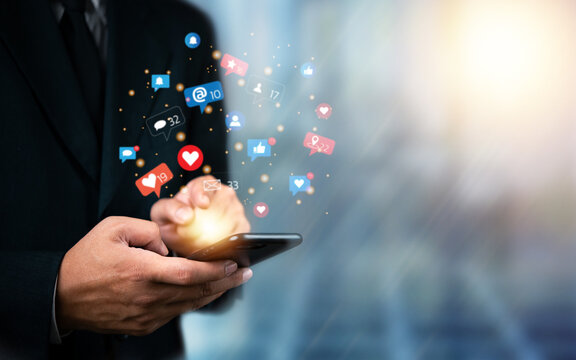 Social media marketing concept. Businessman with digital network, engagement, and marketing connecting through social apps, likes, comments, and notifications on mobile phone. internet technology.
