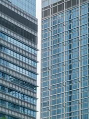 Fototapeta premium Close-up view of two modern skyscrapers in Hong Kong, showcasing their glass and steel facades. The image emphasizes architectural detail and urban density.