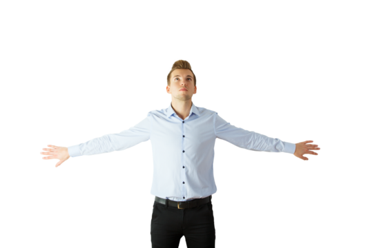 A man standing in a blue shirt with arms extended wide, looking upward, isolated on a white background. Concept of freedom and confidence